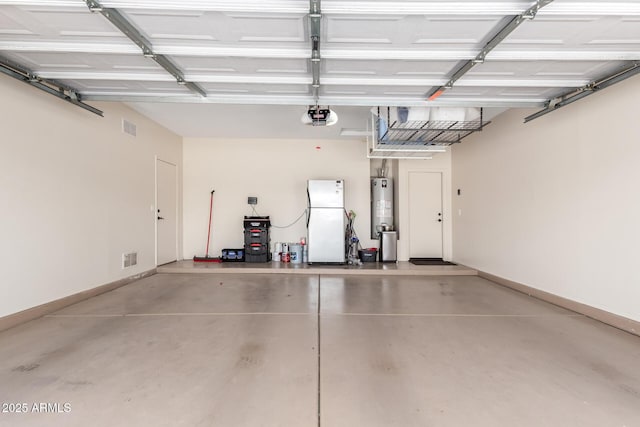 garage with visible vents, freestanding refrigerator, baseboards, a garage door opener, and water heater