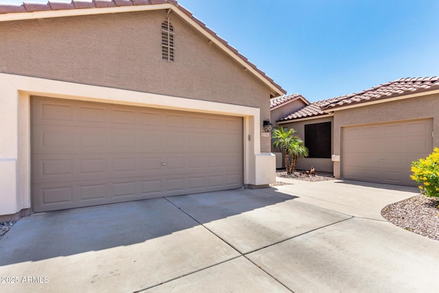 view of front of home featuring concrete driveway, a tile roof, and stucco siding