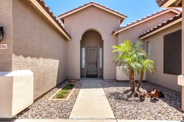 property entrance with a tile roof and stucco siding