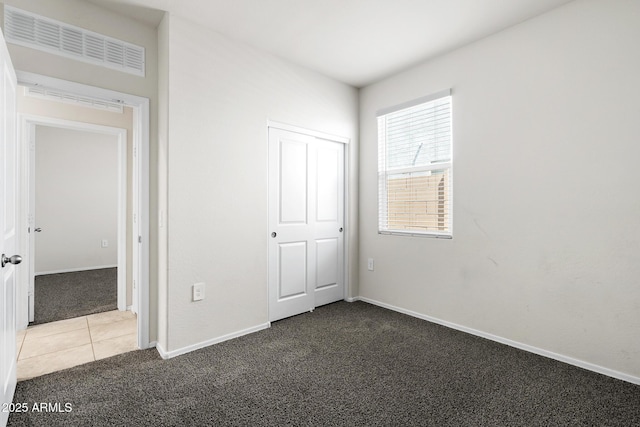 5269 E Gummite Dr, San Tan Valley, AZ 85143 - unfurnished bedroom with tile patterned floors, a closet, carpet flooring, baseboards, and visible vents