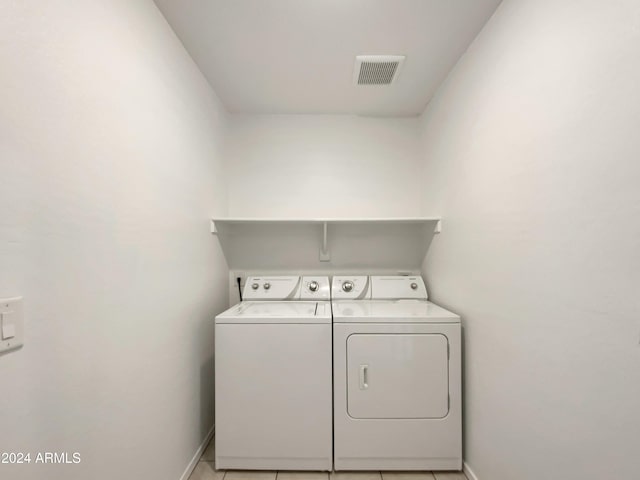 clothes washing area with independent washer and dryer and light tile patterned flooring