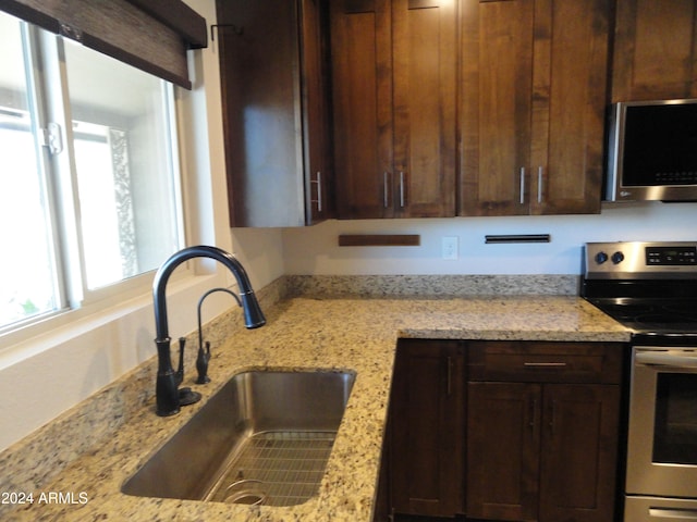 kitchen featuring light stone countertops, stainless steel appliances, and sink