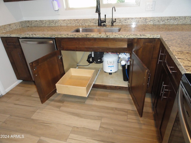 details with light stone counters, dark brown cabinetry, sink, and light wood-type flooring