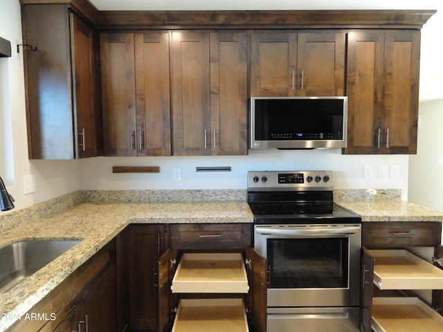 kitchen featuring dark brown cabinetry, light stone counters, sink, and stainless steel appliances