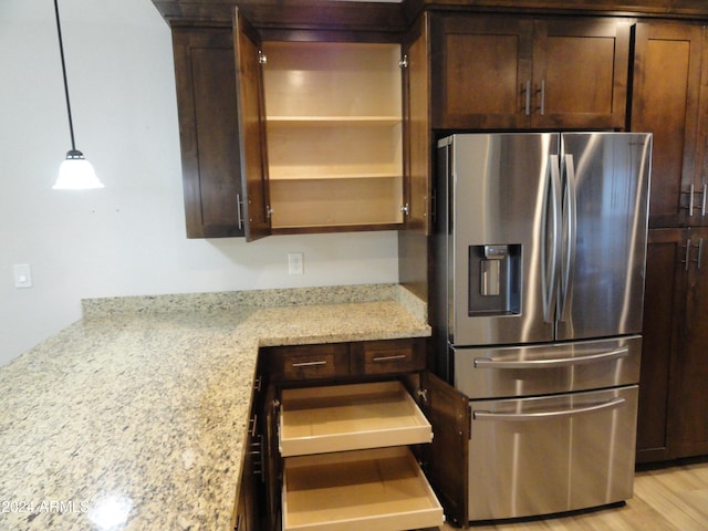 kitchen featuring decorative light fixtures, light hardwood / wood-style floors, light stone counters, and stainless steel fridge with ice dispenser