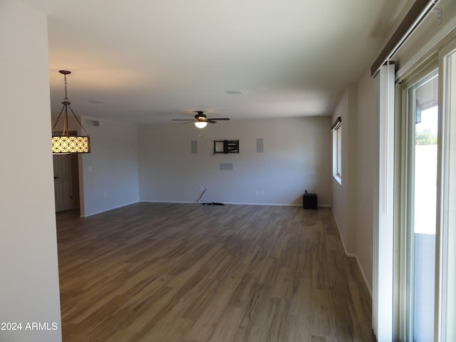 unfurnished living room featuring ceiling fan and dark wood-type flooring