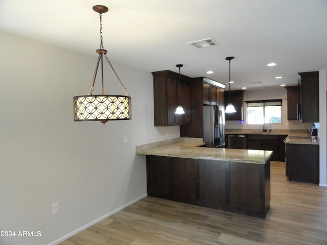 kitchen with kitchen peninsula, pendant lighting, stainless steel appliances, and light hardwood / wood-style floors