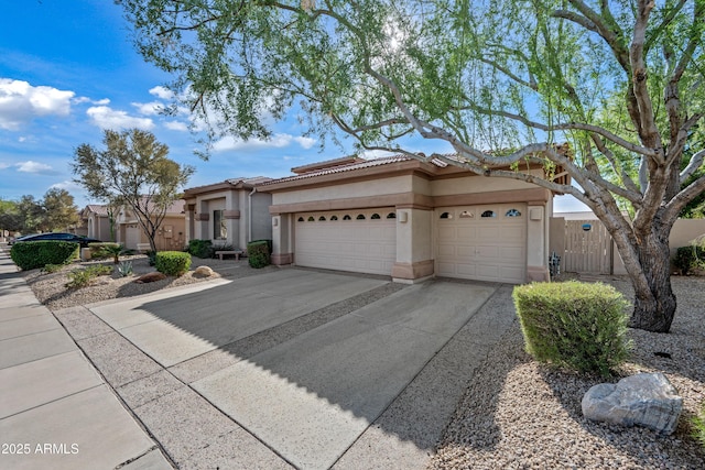 view of front of home featuring stucco siding, an attached garage, fence, driveway, and a tiled roof