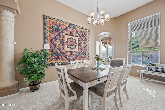 carpeted dining area featuring arched walkways, baseboards, ornate columns, and an inviting chandelier