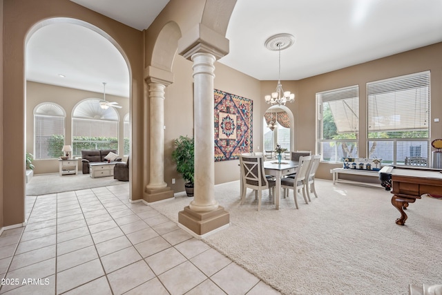 dining room featuring light carpet, decorative columns, arched walkways, a chandelier, and light tile patterned flooring