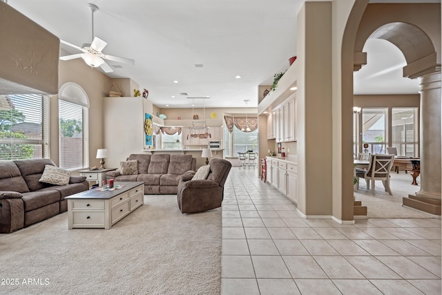 living area featuring a healthy amount of sunlight, light tile patterned floors, arched walkways, and ornate columns