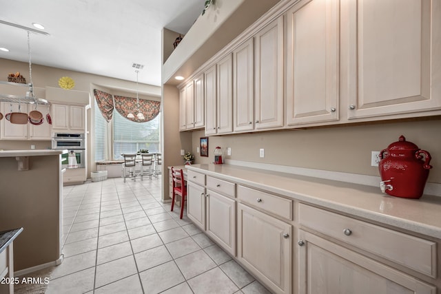 kitchen featuring light tile patterned floors, visible vents, decorative light fixtures, light countertops, and stainless steel double oven