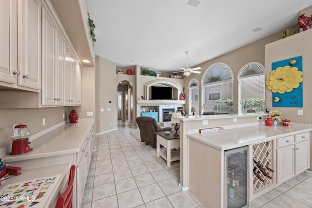 kitchen with arched walkways, wine cooler, open floor plan, light countertops, and a fireplace