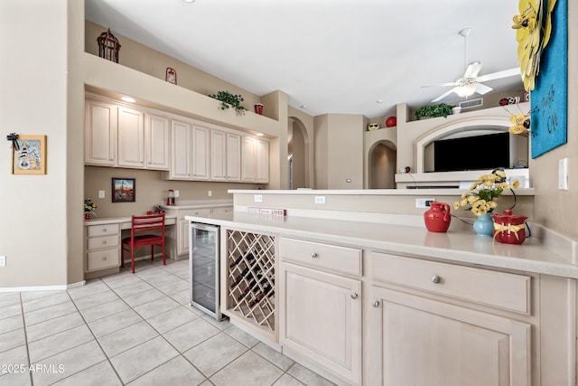 kitchen with beverage cooler, a ceiling fan, light countertops, cream cabinetry, and light tile patterned flooring