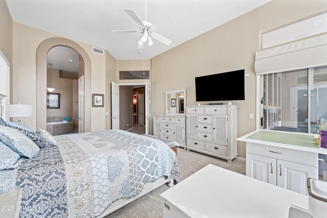 bedroom with arched walkways, connected bathroom, light carpet, visible vents, and a ceiling fan