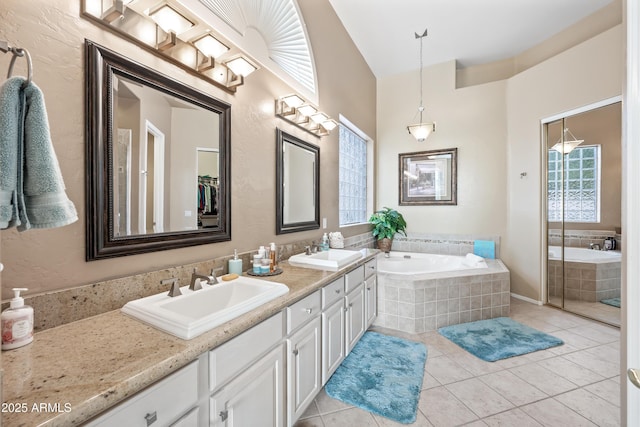 full bathroom with tile patterned flooring, a garden tub, a sink, and double vanity