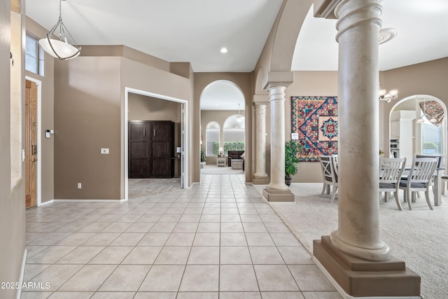 entrance foyer featuring arched walkways, light tile patterned floors, plenty of natural light, and decorative columns