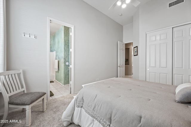 bedroom with light tile patterned floors, light carpet, visible vents, vaulted ceiling, and a closet