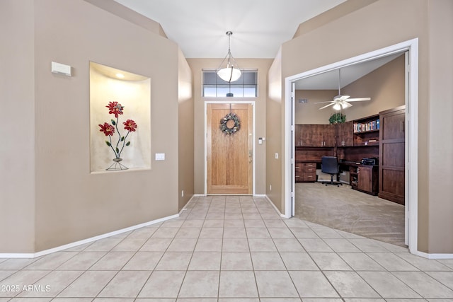 foyer entrance with a ceiling fan, light carpet, baseboards, and light tile patterned floors