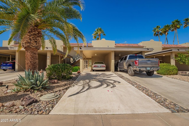 view of front of property with driveway, an attached carport, and a tiled roof