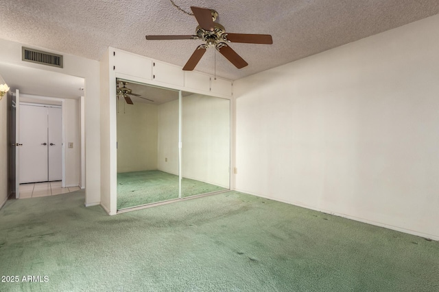 unfurnished bedroom with visible vents, a ceiling fan, light colored carpet, a textured ceiling, and a closet