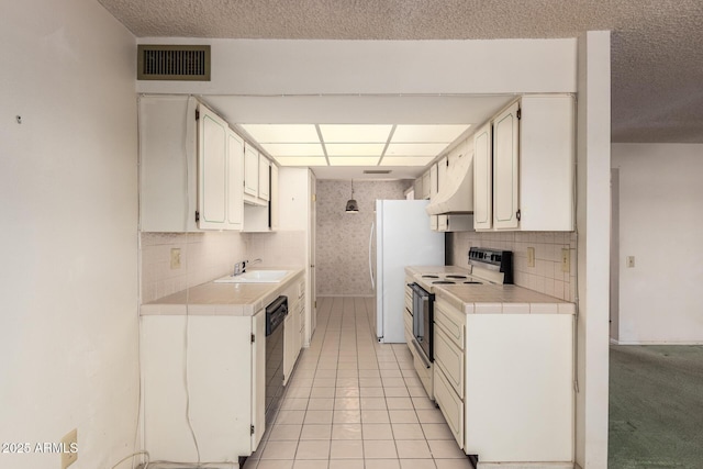 kitchen featuring under cabinet range hood, visible vents, white electric stove, and tile countertops