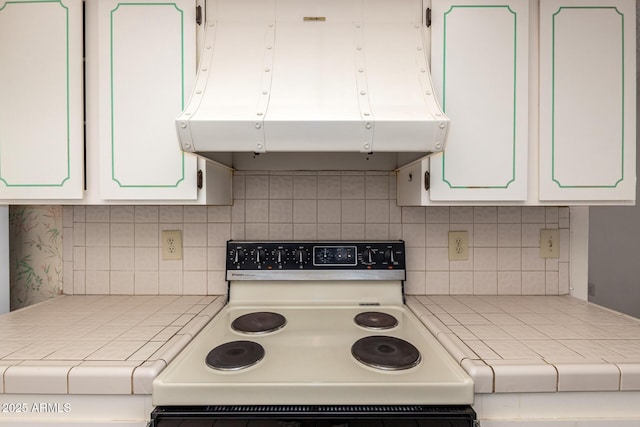 kitchen featuring tile counters, white cabinets, electric range oven, and exhaust hood