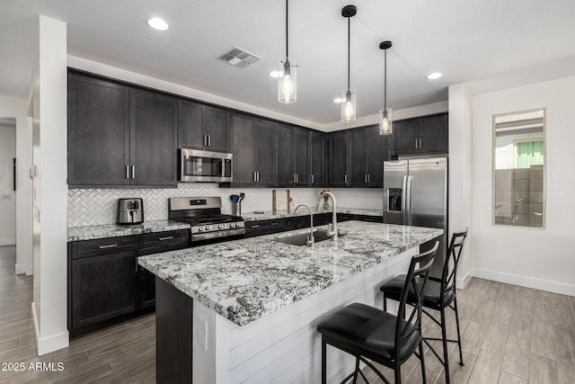 1567 W Camina Plata, San Tan Valley, AZ 85140 - kitchen with appliances with stainless steel finishes, a kitchen bar, tasteful backsplash, light stone counters, and recessed lighting