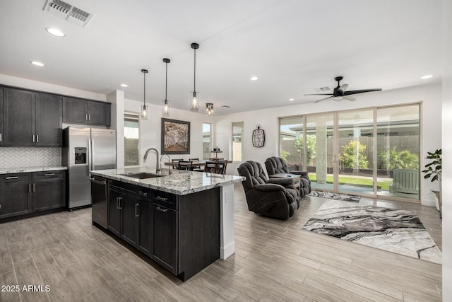 1567 W Camina Plata, San Tan Valley, AZ 85140 - kitchen featuring stainless steel appliances, light wood-type flooring, recessed lighting, light stone countertops, and open floor plan