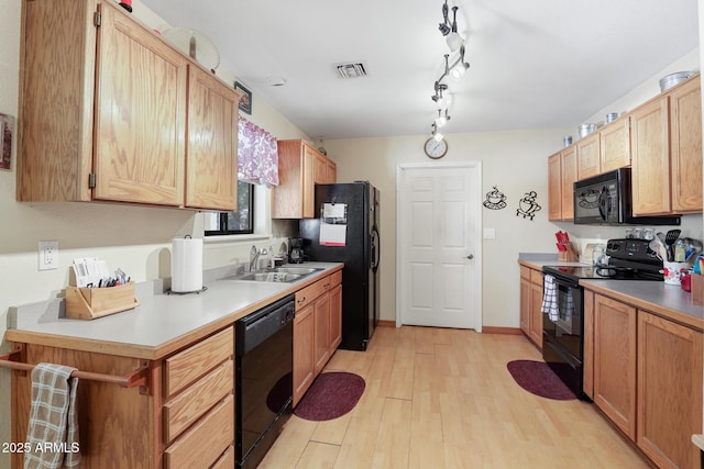 kitchen with baseboards, visible vents, a sink, black appliances, and light wood-style floors