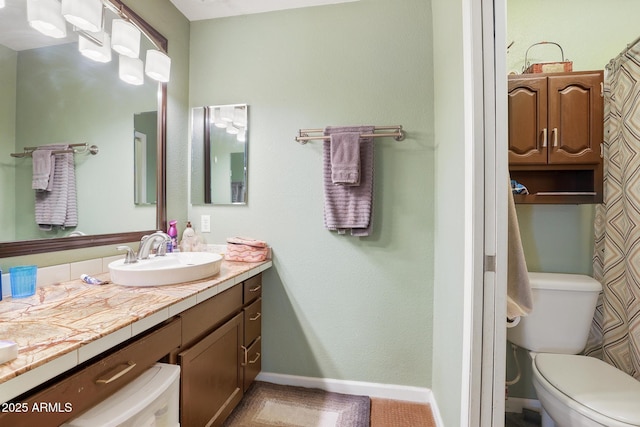 full bath featuring toilet, vanity, and baseboards