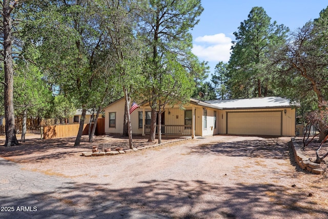 view of front of home featuring a garage, covered porch, driveway, and fence