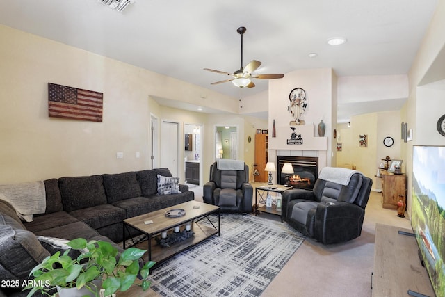 living room featuring a ceiling fan, visible vents, lofted ceiling, light carpet, and a glass covered fireplace