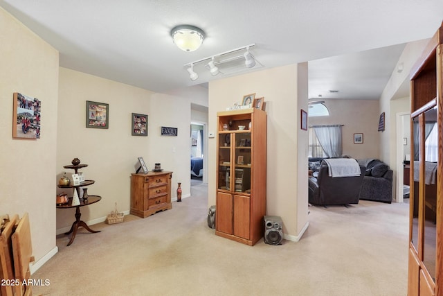 corridor with track lighting, baseboards, and carpet floors