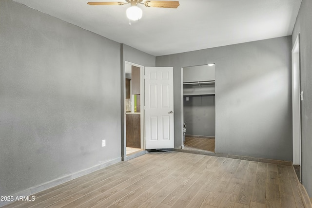 unfurnished bedroom featuring ceiling fan, light hardwood / wood-style floors, and a closet