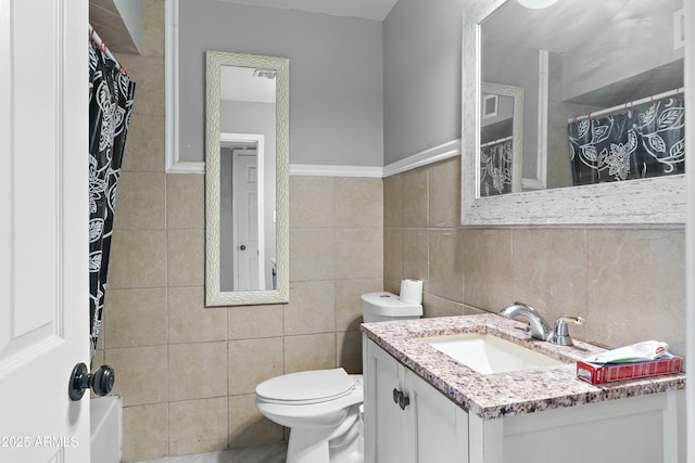 bathroom with vanity, toilet, and tile walls