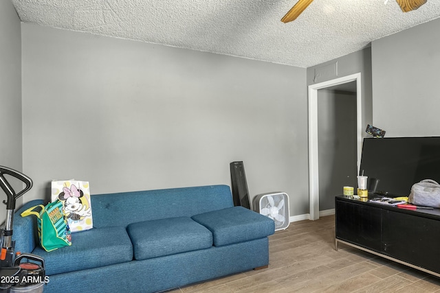 living room featuring light wood-type flooring, a textured ceiling, and ceiling fan