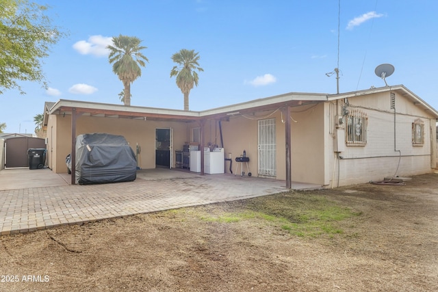 back of house with a shed and separate washer and dryer