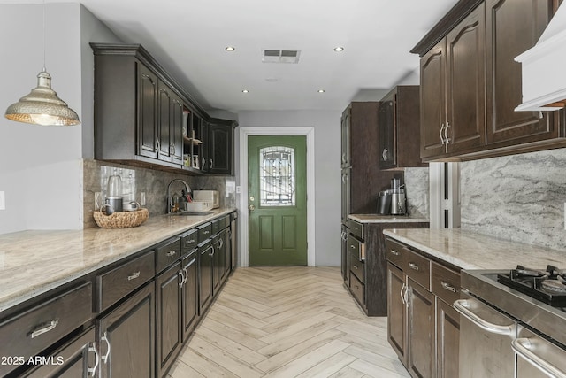 kitchen featuring sink, light stone counters, light parquet floors, pendant lighting, and decorative backsplash