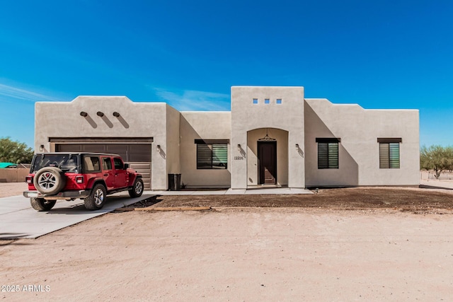 pueblo-style home featuring a garage, driveway, and stucco siding