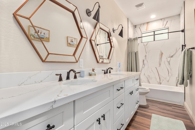 full bathroom featuring double vanity, wood finished floors, a sink, and toilet