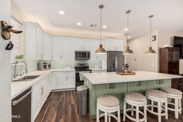 kitchen with white cabinets, dark wood-style flooring, stainless steel appliances, and a sink