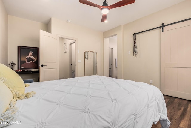 bedroom featuring ceiling fan, a barn door, and wood finished floors