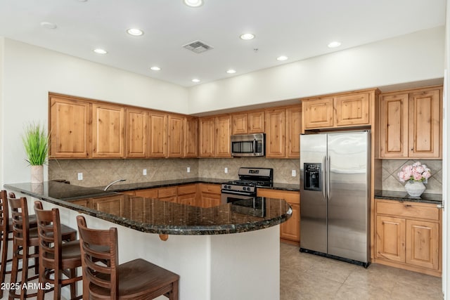 kitchen featuring light tile patterned flooring, stainless steel appliances, a peninsula, visible vents, and dark stone counters