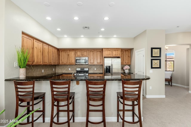 kitchen featuring tasteful backsplash, visible vents, appliances with stainless steel finishes, light carpet, and a peninsula