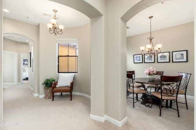 carpeted dining area with baseboards, arched walkways, and a notable chandelier