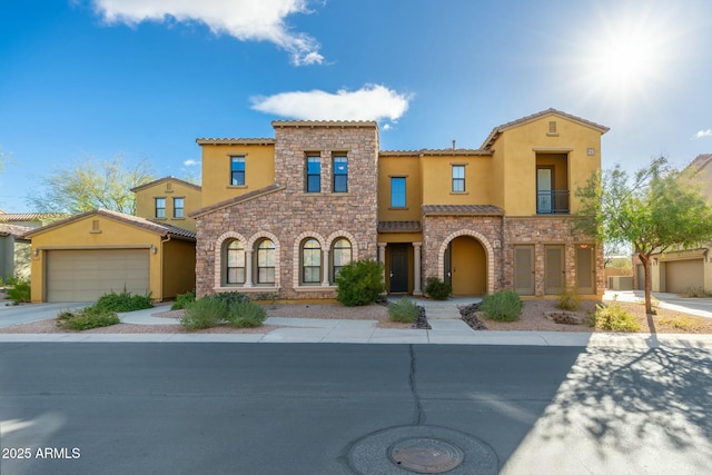 mediterranean / spanish house featuring a garage, stone siding, concrete driveway, and stucco siding