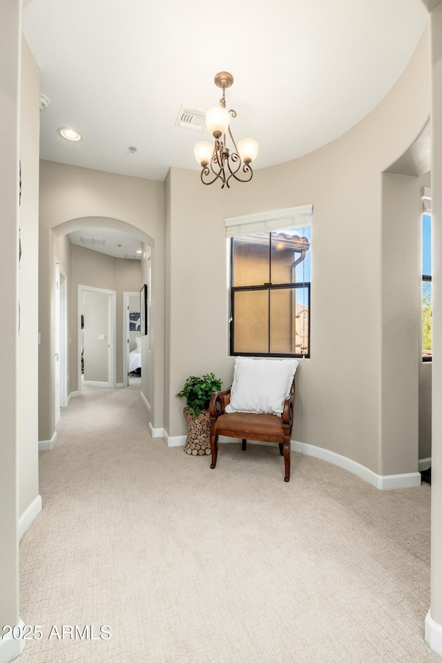 hall with carpet floors, arched walkways, visible vents, and plenty of natural light