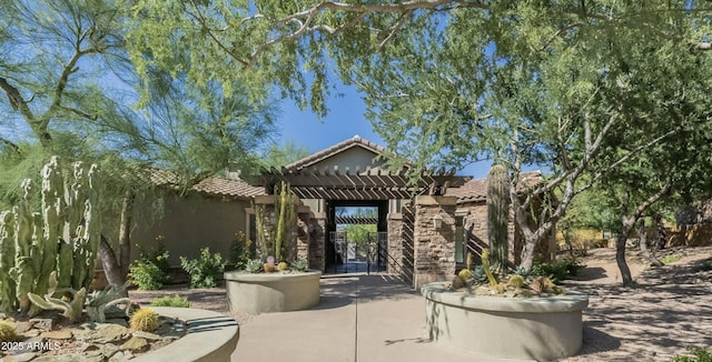 view of exterior entry with stucco siding, stone siding, a pergola, and a tiled roof