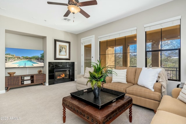 living area with carpet floors, a tile fireplace, visible vents, and ceiling fan